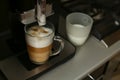 The process of whipping milk with steam. A cup of milk and a coffee machine for whipping. Spout in a cup.