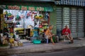 Processed pet food business open at night. Two barefoot aged men chatting, having a conversation in front of the shop, sitting on