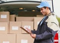 Processing his deliveries for the day. a delivery man writing on a clipboard while standing next to a van full of boxes. Royalty Free Stock Photo