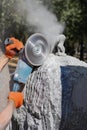 Processing of wild stone gabbro granite with an angle grinder, the sculptor creates a masterpiece. Royalty Free Stock Photo