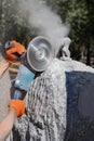 Processing of wild stone gabbro granite with an angle grinder, the sculptor creates a masterpiece.