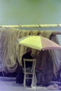 PROCIDA, ITALY, 1975 - A fisherman repairs his fishing nets on the pier in the shade of a parasol