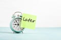 Procrastination, delay concept. Bad time management. Word later sticked to alarm clock Royalty Free Stock Photo