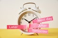 Procrastination, delay and postpone concept. Alarm clock with sticky notes later, tomorrow, next day and after on yellow