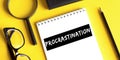 Procrastination. Motivation. Concept meaning delay or put off something boring written on a notepad on a yellow desk. View from