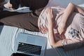 Procrastination, rest from work: a woman rests in bed next to a computer.