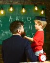 Prodigy child concept. Boy, child in graduate cap discussing scribbles on chalkboard while teacher listening. Teacher