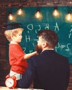 Prodigy child concept. Boy, child in graduate cap discussing scribbles on chalkboard while teacher listening. Teacher