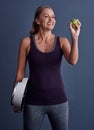 The product of a proper diet. Studio shot of an attractive mature woman holding an apple and a weightscale against a Royalty Free Stock Photo