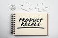 PRODUCT RECALL. Notepad, puzzle pieces and gear on white office table Royalty Free Stock Photo