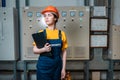 Production inspection. A young female worker in a uniform and a protective helmet, holding a folder. The concept of industrial