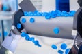Production line - many blue plastic bottle caps falling from conveyor belt