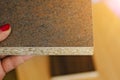 production, manufacture and woodworking industry concept - close up hand holds a sample of chipboard with a decorative coating Royalty Free Stock Photo