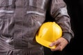 A production worker in workwear with a protective helmet in his hand. Special workwear for employees