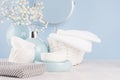 Products for body and skin care in light blue ceramic bowls, silver cosmetic bag, circle mirror and white flowers on wood table. Royalty Free Stock Photo