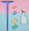 Products for cleaning glass windows. Sponges, window mop, sprinkler cleanser on a blue pink pastel background. Royalty Free Stock Photo