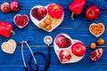 Products good for heart and blood vessels. Vegetables, fruits, nuts in heart shaped bowl near stethoscope on blue wooden Royalty Free Stock Photo