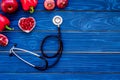 Products good for heart and blood vessels. Vegetables, fruits, nuts in heart shaped bowl near stethoscope on blue wooden Royalty Free Stock Photo