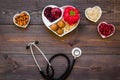 Products good for heart and blood vessels. Vegetables, fruits, nuts in heart shaped bowl near stethoscope on dark wooden Royalty Free Stock Photo