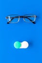 Products help see better. Glasses with transparent optical lenses and eye lenses on blue background top view copy space Royalty Free Stock Photo