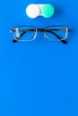 Products help see better. Glasses with transparent optical lenses and eye lenses on blue background top view copy space Royalty Free Stock Photo