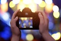 Profesional digital camera in hands. Blue and yellow bokeh in background Royalty Free Stock Photo