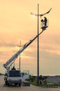 Profession repair and maintenance of street lamps - car with crane lifted an electrician to replace bulbs at sunset in evening.