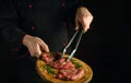 Professiona chef holds a cutting board with raw beef steaks before barbecue. Preparation for roasting meat with rosemary and Royalty Free Stock Photo