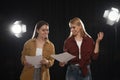 Professional actresses reading scripts during rehearsal in theatre
