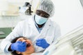 Professional dentist performing teeth treatment to woman at dental clinic