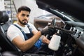 Close up of worker of auto service station, cleaning modern vehicle interior with tornado air gun.