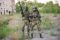 A professional airsoft player stands in a big helmet and a machine gun and with his partner.