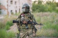 Professional airsoft player stands in a big helmet and a machine gun.