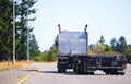 Big rig semi truck with flat bed trailer turn on road with trees
