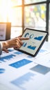 Professional analyzing business data on a tablet with financial charts and documents in a bright office Royalty Free Stock Photo
