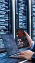 A professional appears anxious while checking a warning message on his phone, surrounded by coding screens in a