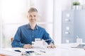 Professional architect posing in the office with an architectural model of a contemporary building