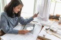 Professional architect women working in designer jobs while using tablet and holding material sample for modern house on the desk Royalty Free Stock Photo