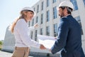 Professional architects in hardhats discussing blueprint while working at construction site