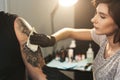 Professional artist wiping finished tattoo with hygienic napkin