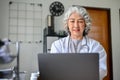 Professional Asian aged female doctor concentrating on her medical research on laptop Royalty Free Stock Photo