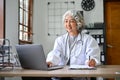 Professional Asian aged female doctor concentrating on her medical research, using laptop Royalty Free Stock Photo