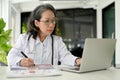 Professional Asian aged female doctor specialist working at her desk, using laptop computer Royalty Free Stock Photo