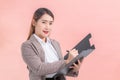 Professional Asian business women writing documents on the clipboard in hand while working at home isolated on peach color Royalty Free Stock Photo