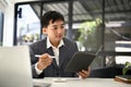 A professional Asian businessman checks his meeting schedule on his planner book