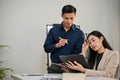 Professional Asian businessman concentrated on working with his female coworker in the office