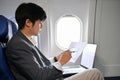 Professional Asian businessman concentrating analyzing a financial data during the flight