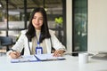 Professional Asian businesswoman reading and reviewing business report at her desk Royalty Free Stock Photo