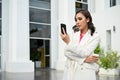 Professional Asian businesswoman standing outside of the building, using her smartphone Royalty Free Stock Photo