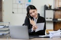 Professional Asian female accountant focuses on her sales accounts using a calculator and laptop Royalty Free Stock Photo